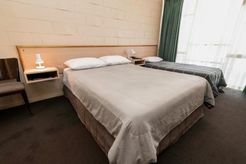 two beds in a hotel room with a window at The Prince Mark Motel in Eumemmerring