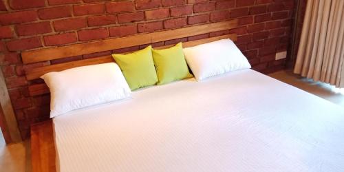 a white bed with two pillows and a brick wall at Eco Breeze - Unawatuna in Unawatuna