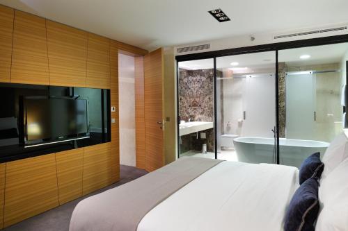 a bedroom with a bed and a tv and a tub at Radisson Blu Plaza Hotel Ljubljana in Ljubljana