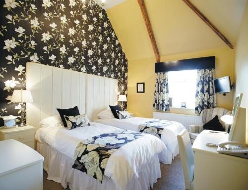 two beds in a room with yellow walls at Cotford Hotel in Great Malvern