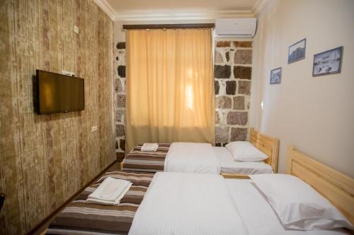 a room with three beds and a tv on a wall at Studio Boutique Hotel at Cascade in Yerevan