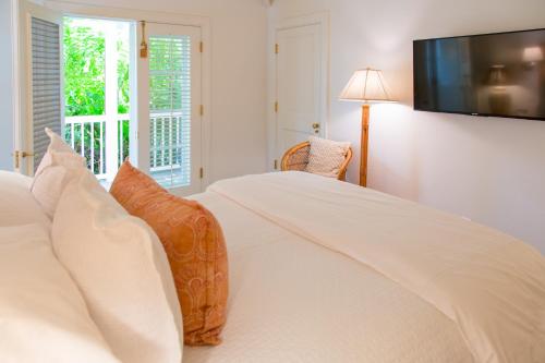 a bedroom with a white bed with a television on the wall at Eleven Bahama House in Harbour Island