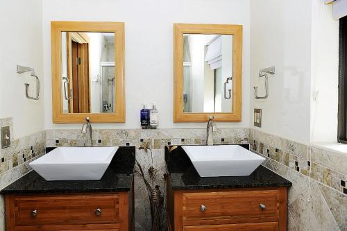 two sinks in a bathroom with two mirrors at Sheridan House Inn- Adult Only Accommodation in Williams