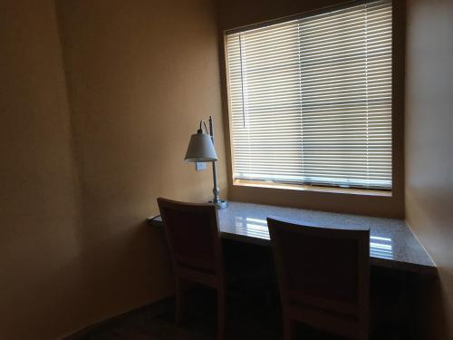 a desk with two chairs and a lamp and a window at El Rancho Dolores at JT National Park in Twentynine Palms