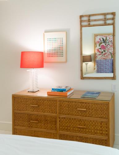 a wooden dresser with a lamp and a mirror at Eleven Bahama House in Harbour Island