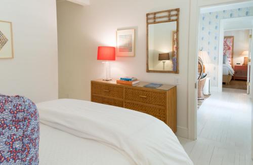 a bedroom with a bed with a lamp and a mirror at Eleven Bahama House in Harbour Island