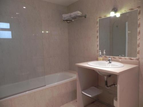 a bathroom with a sink and a tub and a mirror at Lareira do Pinheirinho in Charneca