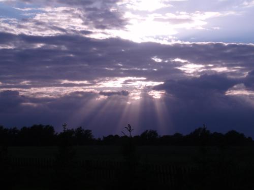 a cloudy sky with the sun shining through the clouds at Siedlisko Sabinowo in Węgorzewo