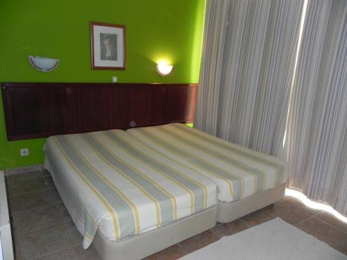 a bed in a room with a green wall at Lareira do Pinheirinho in Charneca