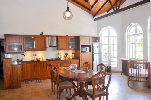 Una cocina con gabinetes de madera y una mesa con sillas. en Samindra Villa, en Kandy