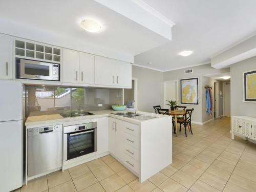 a kitchen with white appliances and a dining room at Barrenjoey at Iluka Resort Apartments in Palm Beach