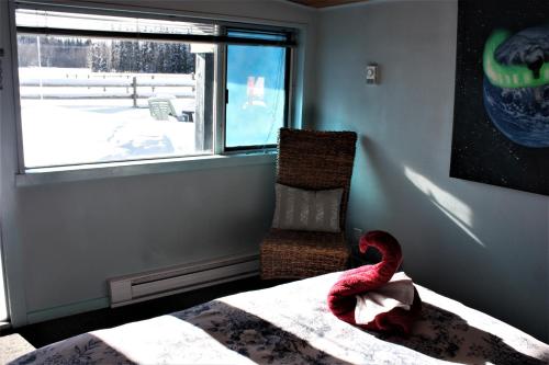 a bedroom with a bed and a window and a chair at Woodhouse Cottages And Ranch in Prince George