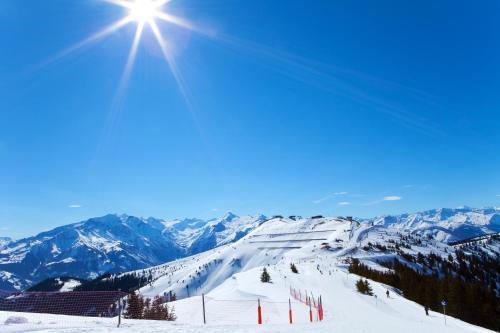 a snow covered ski slope with the sun in the sky at Grand Hotel Zell am See in Zell am See
