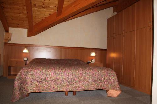 a bedroom with a bed and a wooden ceiling at Garnì Goccia d'Oro in Cavalese