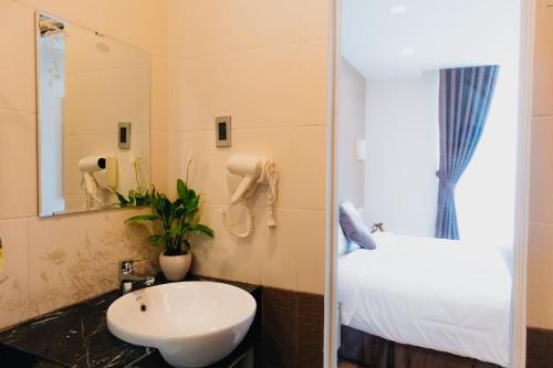 un bagno con un lavandino, un letto e uno specchio di Silent Night Dem Lanh Hotel a Da Lat