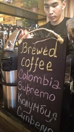 a person holding a sign that says brewed coffee colombinian at Madanur Hotel in Karakol