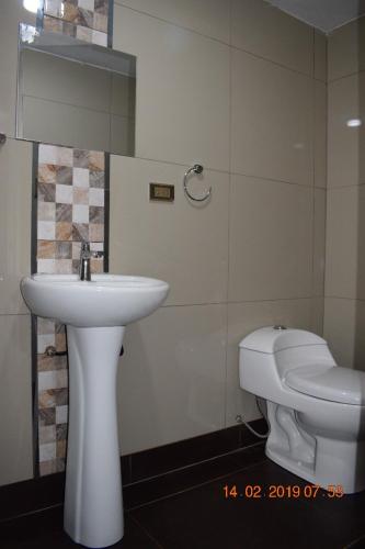 a bathroom with a white sink and a toilet at Arum Qurpawasi Hospedaje in Cabanaconde
