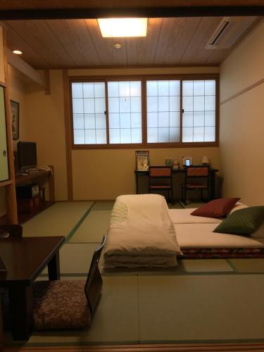 een kamer met 2 bedden, een tafel en ramen bij Ryokan Sawaya Honten in Kyoto
