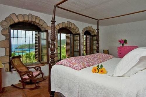 a bedroom with a bed and a chair and windows at Sugar Reef Bequia - Adults Only in Crescent Beach