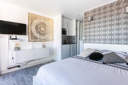 a white bedroom with a bed and a flat screen tv at Studio naturiste venus panoramic view in Cap d'Agde