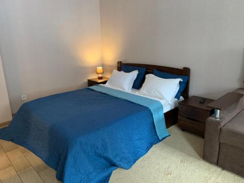 a bedroom with a bed with a blue comforter and pillows at Apart Hotel Smart Studio in Kharkiv