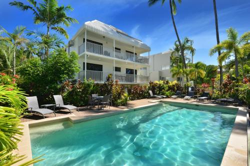 a swimming pool in front of a house at Tropical Reef Apartments in Port Douglas