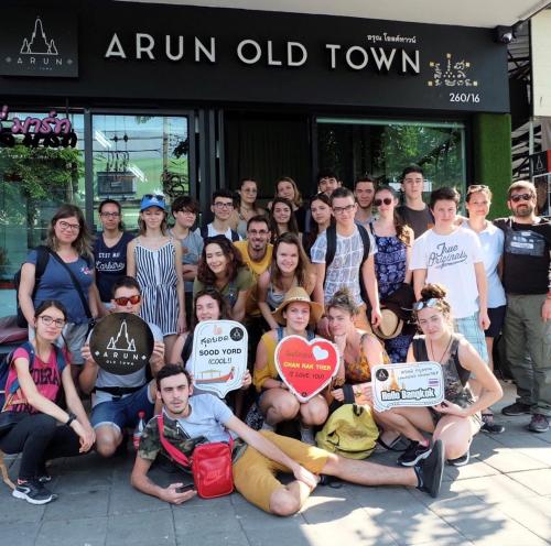 a group of people posing for a picture with signs at Arun Old Town in Bangkok