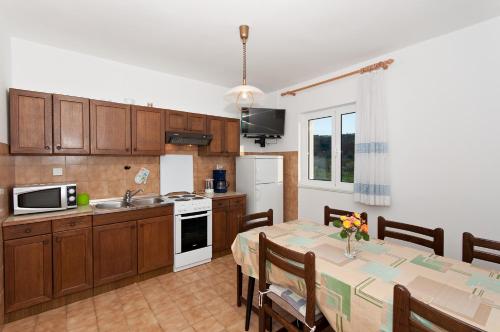 a kitchen and dining room with a table with chairs and a kitchen with a table at Apartment Lopar 12 in Lopar