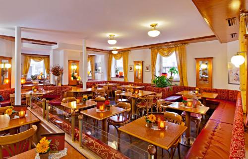 un restaurante con mesas de madera y sillas rojas en Hotel Greinwald, en Marktoberdorf