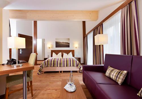 um quarto de hotel com uma cama e um sofá roxo em Hotel Greinwald em Marktoberdorf