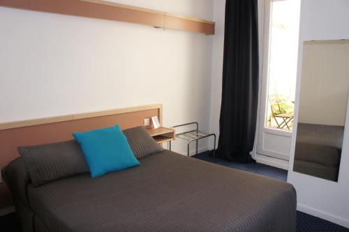 Un dormitorio con una cama con una almohada azul encima. en Hôtel Edgar Quinet, en París