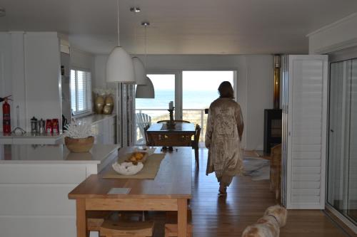 a woman in a kitchen looking out at the ocean at Thyme & Tide Beach Villa in Yzerfontein
