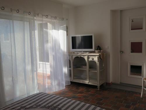 a bedroom with a television on a cabinet with a window at chez Annick in La Flèche