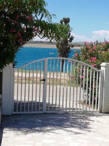 a white gate leading to a beach with the ocean at Villa Pagar - with jacuzzi - Renovated in 2022 in Povljana