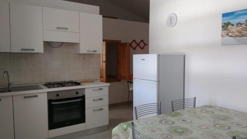 Una cocina con gabinetes blancos y un refrigerador blanco. en Budoni Apartments, en Budoni