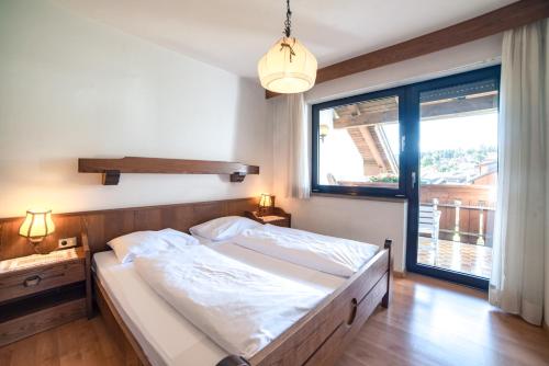 - une chambre avec un grand lit et une grande fenêtre dans l'établissement Sonnen Residence, à Collalbo