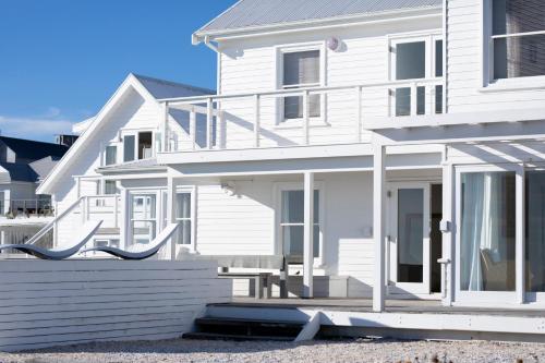 una casa blanca con un porche delante en Pearl Bay Beach Home, en Yzerfontein