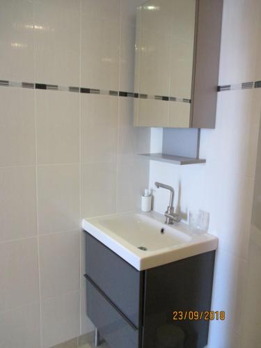 a white bathroom with a sink and a mirror at Port nature in Cap d'Agde