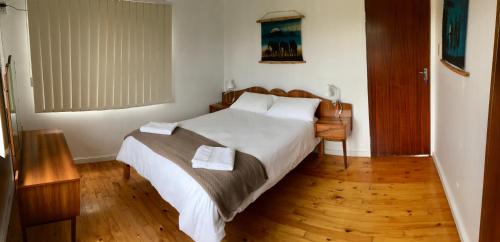 um quarto com uma grande cama branca e pisos em madeira em David Bongers Still Bay Holiday Home em Stilbaai