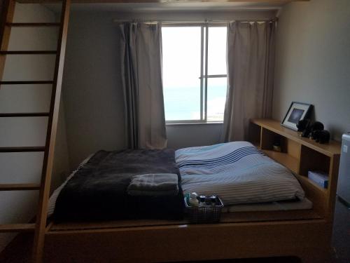 宮崎市にあるOcean Home Guest Houseのベッドルーム(二段ベッド1組、窓付)