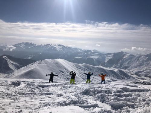 four people standing on top of a snow covered mountain at RezoHut in Gudauri