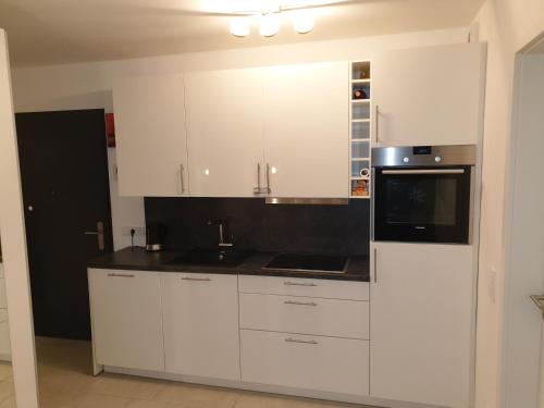 a white kitchen with white cabinets and a microwave at Schicke Ferienwohnung Darmstadt Bessungen in Darmstadt