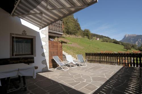 a patio with chairs and a table and a hill at Oberpiskoihof in Funes