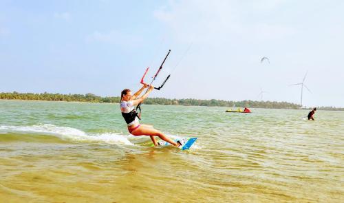 a woman is on a surfboard in the water at Roshanne Beach Resort in Kalpitiya