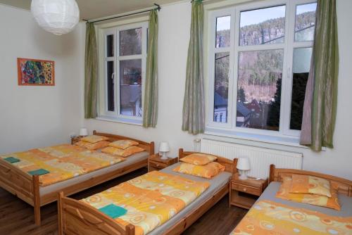 two beds in a room with two windows at U Kosti - Bohemian Switzerland in Děčín
