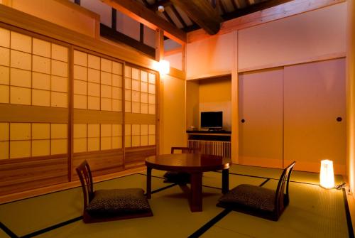 a room with a table and chairs and a tv at Miyama Ouan Kyoritsu Resort in Takayama