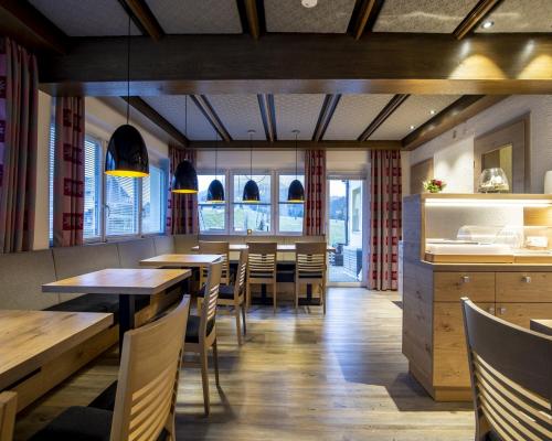 a restaurant with wooden tables and chairs and windows at Gästehaus Boersch in Riezlern