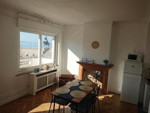 une salle à manger avec une table et une cuisine avec une fenêtre dans l'établissement Le Bain de mer, à Boulogne-sur-Mer