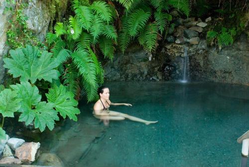 a woman sitting in a pool of water with a waterfall at Puyuhuapi Lodge & Spa in Puerto Puyuhuapi