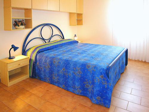 a bedroom with a bed with a blue comforter at Appartamenti Nasse in Bibione